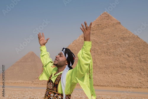 Bild auf Leinwand Triumphant Arab man in bright embroidered yellow robe and turban raises both arm