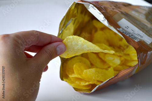 Fotografie Person reaching into an open metallic bag and pulling out a single golden crispy