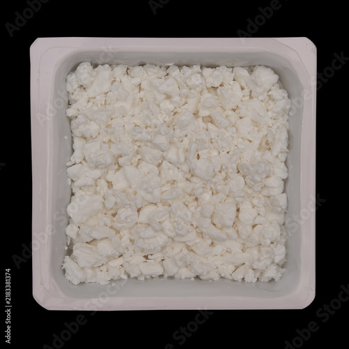 Cottage cheese in container isolated on black background. Top view. Soft cultured curd
