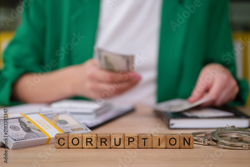 Konstfotografi Stacks of cash sit on a desk alongside handcuffs and notebooks, as a person counts more money, illustrating the theme of corruption and financial misconduct in a corporate environment