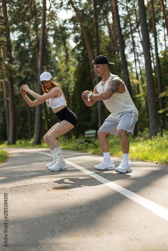 Obraz na płótnie Athletic couple doing deep squats together during an outdoor fitness workout on a park path
