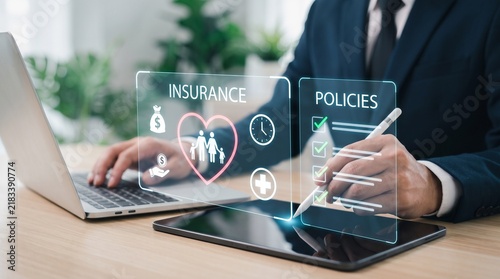 Business professional using a tablet and laptop to manage insurance policies at a wooden desk with uses digital