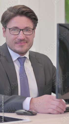 Young Businessman Looking at Camera while using Desktop Computer, Vertical Video