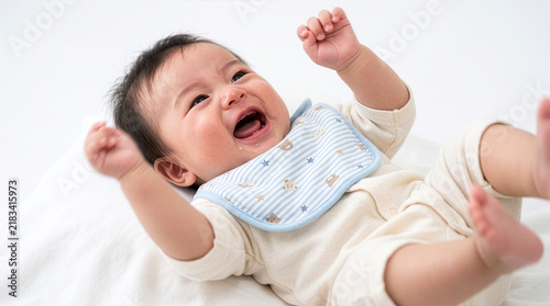 Happy baby boy laughing and kicking legs on bed