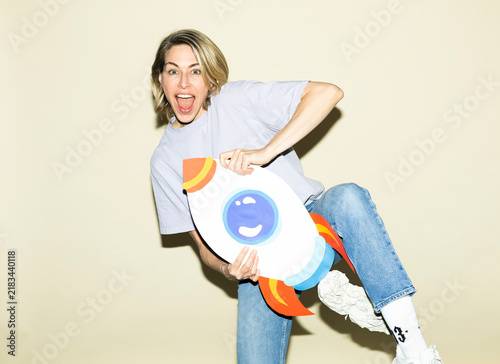 Excited woman holds a paper rocket indoors for business growth