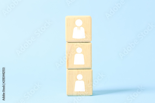 Cuadro en lienzo Stacked wooden blocks with people icons represent business hierarchy, leadership, management, organization structure and teamwork on a blue background with copy space for corporate use