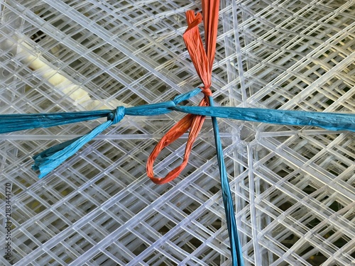 Fotografie Transparent Plastic Grid Mesh Bound with Blue and Orange Raffia String
