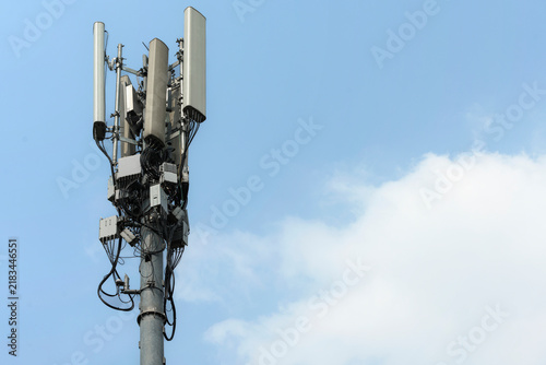 Telecommunication cell tower antenna against a blue sky with clouds. Concept of communication network and connection technology