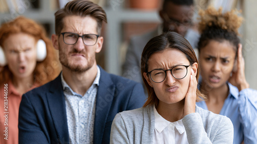 A diverse group of individuals displaying frustration and annoyance in a professional setting, highlighting the impact of stress on emotional well-being and interpersonal dynamics.