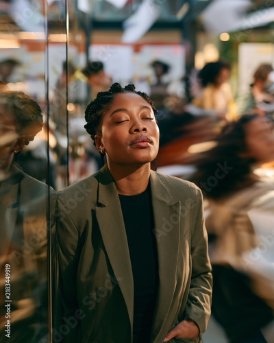 Worker stands still in a busy setting with eyes closed, showing disengagement