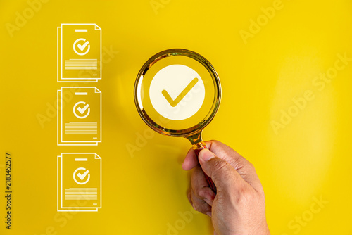 Bild auf Leinwand Hand using a magnifying glass to verify documents, checklists and quality standa