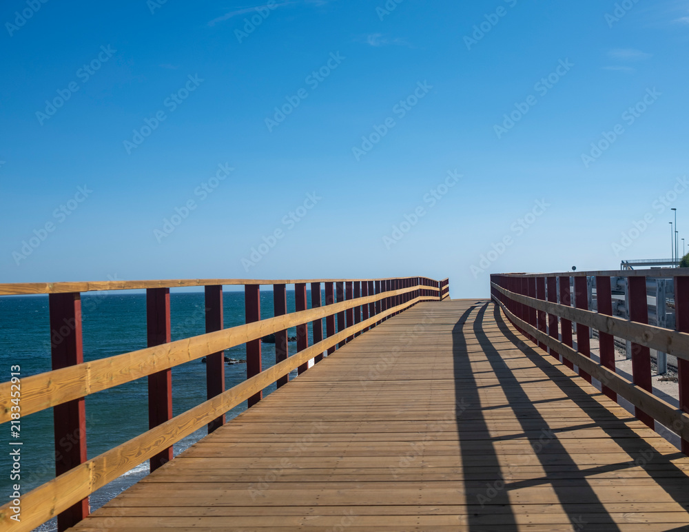 Obraz premium Wooden boardwalk leading towards the Mediterranean Sea in Fuengirola, Spain
