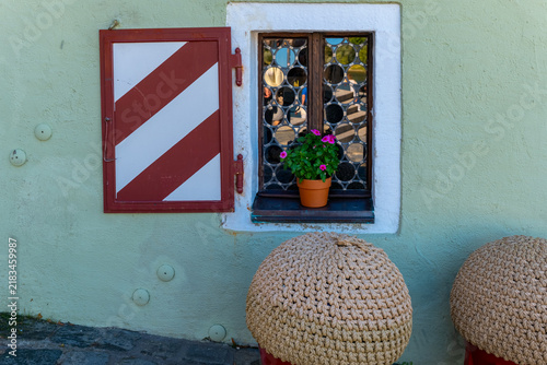 Colorful window with potted plant and decorative elements in a small town