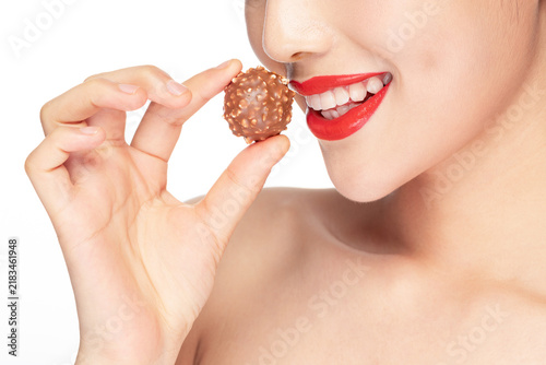 Obraz na plátne Woman holding chocolate candy to her mouth smiling
