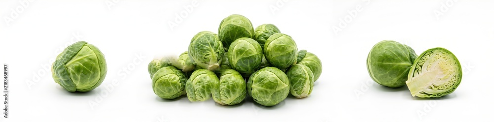 Fototapeta premium Brussels sprouts are arranged in a pile with a few cut in half. They represent autumn harvest foods popular for recipes. The white background highlights their green color