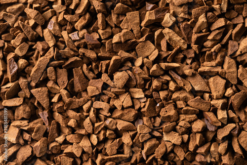 Macro close-up of dry instant coffee granules filling the entire frame. Detailed brown food texture for coffee packaging, beverage advertising, backgrounds and commercial design
