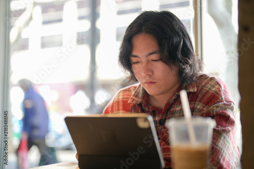 Photography A closer view shows a person looking at a tablet with a cold drink near the front edge of the table