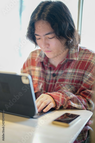 Photography A vertical view shows a person interacting with a tablet while a smartphone lies on the cafe table
