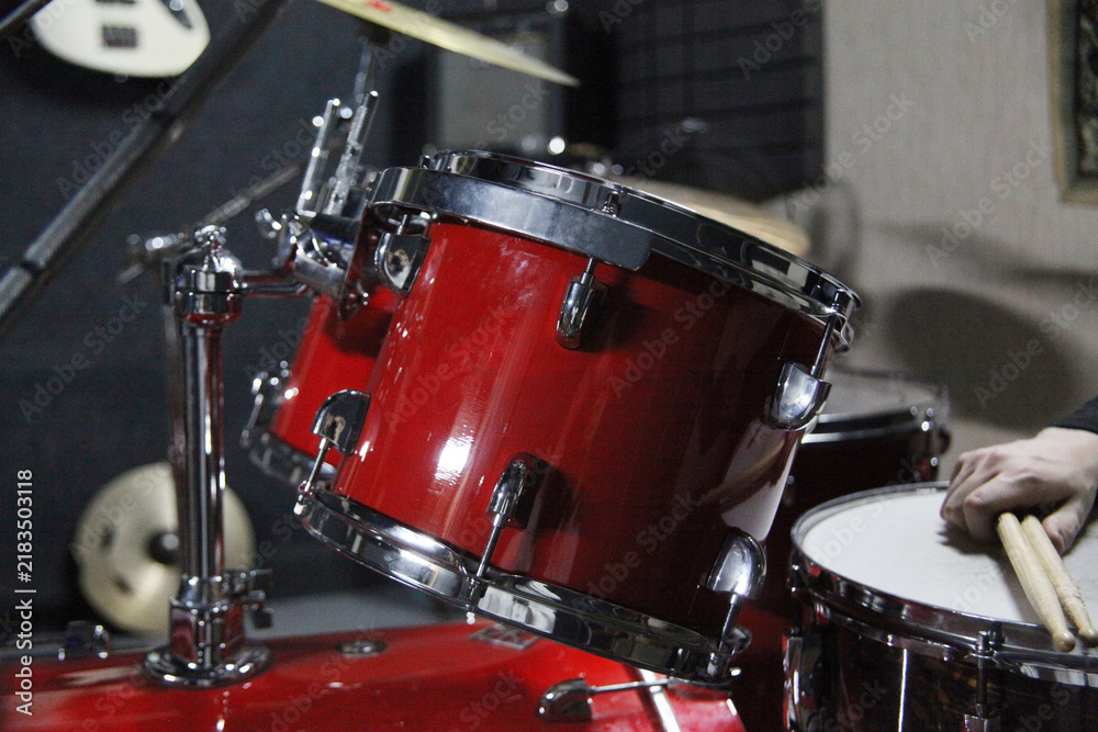 Fototapeta premium A person plays a beat on a red drum kit using wooden drumsticks.