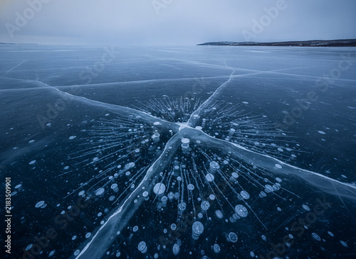 Frostbite Star Crystal Pattern on Frozen Ice Lake Surface. Detailed Snowflake Texture with Bubbles on Cold Winter Background. Artic Frost Design Concept