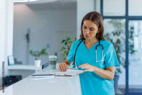 Healthcare worker reviewing patient records at a clinic front desk