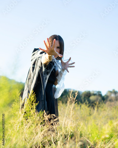 фотографія Woman in Hooded Cloak Casting Spell in Grassy Field