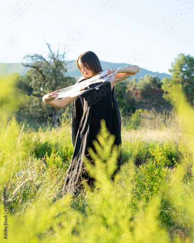 Woman in Black Dress Holding White Veil in Grassy Field