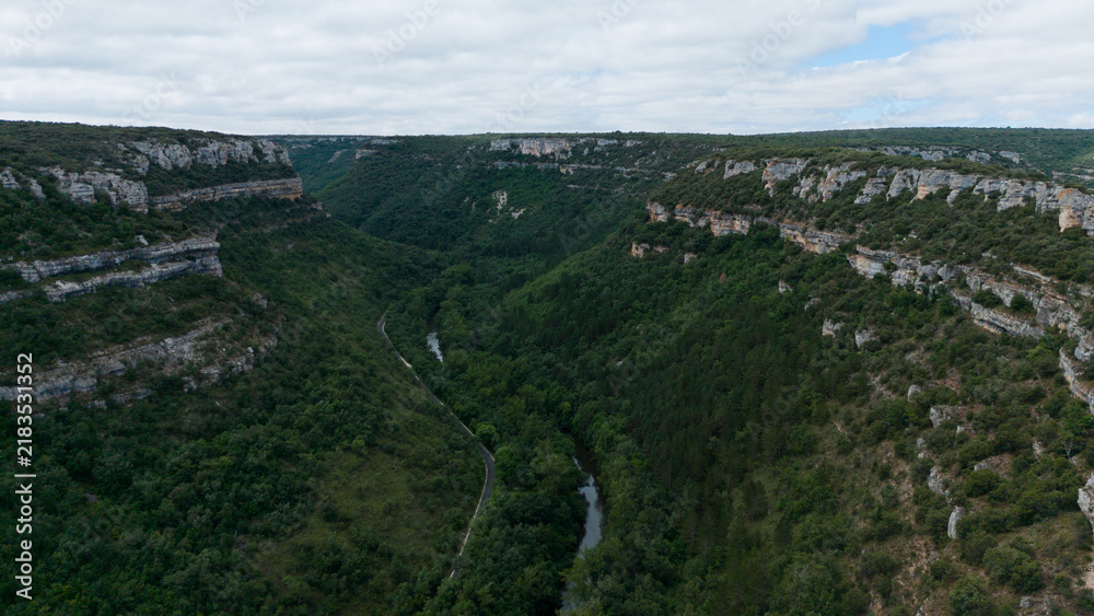 Fototapeta premium serene and majestic aerial view of forested canyon walls and river above rocky cliffs in natural landscape. Risco los camellos, Cascada de Orbaneja del Castillo