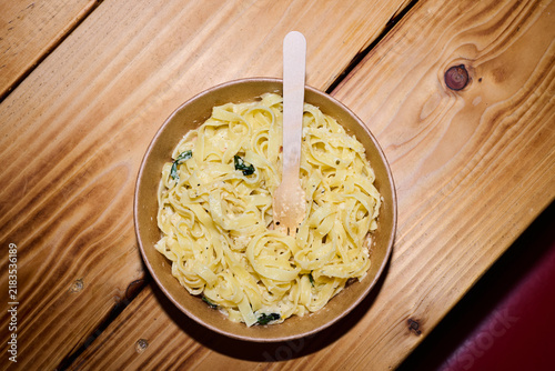 Fotografie Close-up of a plate of pasta on a cardboard plate with a wooden knife in a fast food restaurant