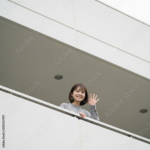 Obraz na płótnie マンションのベランダから手を振る若い日本人女性