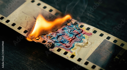 Burning film strip with colorful patterns and smoke creates striking visual effect