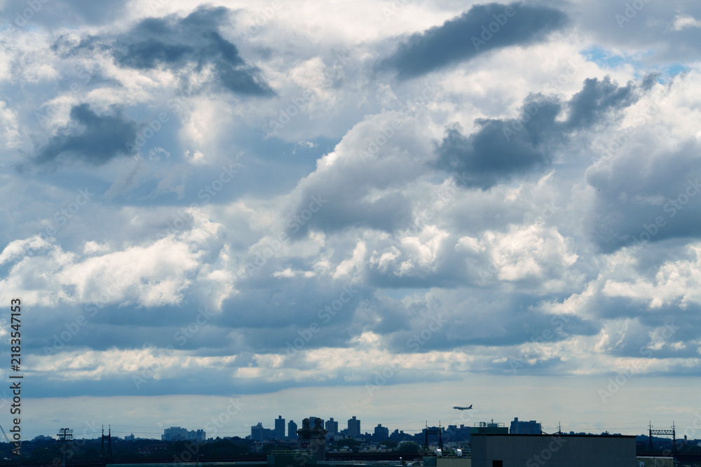Fototapeta premium Dramatic dark storm clouds gathering dramatically over a silhouette city skyline, creating an intense and moody weather atmosphere. 
