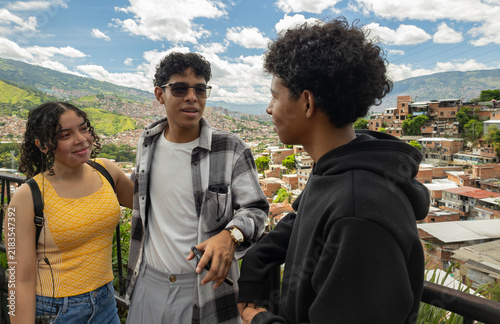 Three young friends enjoying a sightseeing visit at a viewpoint in San Javier, Medellín, Colombia, while observing the urban surroundings