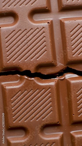 Broken milk chocolate bar rotating slowly. Top view vertical video