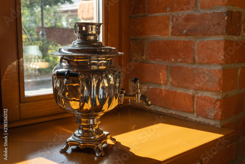 Canvas Print traditional samovar stands on wooden surface near brick wall and window