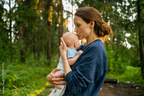 Bild auf Leinwand Mother tenderly holding her baby son and giving a kiss on his forehead, embracin