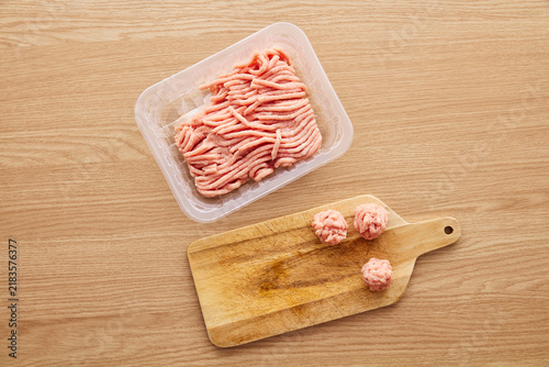 Cuadro en lienzo Raw Minced Meat in Plastic Container and Meatballs on Cutting Board