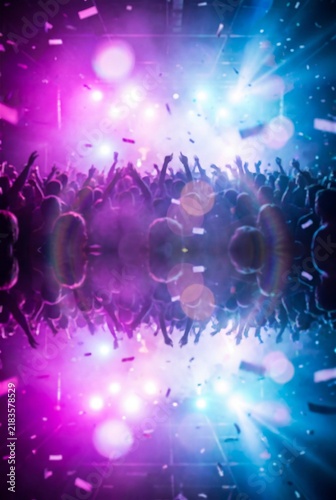Crowd dancing at a nightclub with colorful stage lights and falling confetti