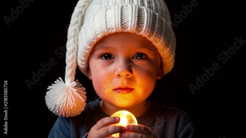 Child Holding Candle in Winter Hat.