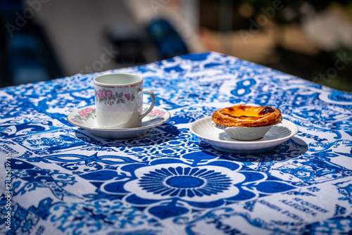 Pastel de nata custard tart with coffee cup on blue tablecloth on