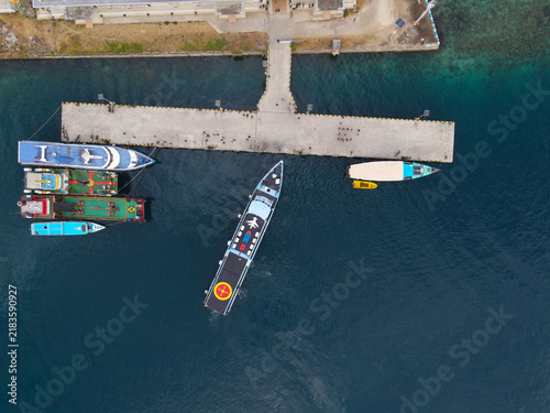 Aerial view of Waisai Harbour with a passenger ferry departing from the pier alongside smaller boats moored in clear blue tropical waters Raja Ampat, Papua Barat Daya, Indonesia.