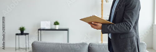 Business person holding clipboard inspecting residential property in modern home int.