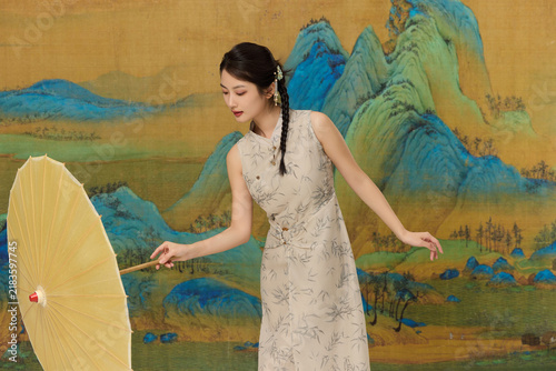 Foto Young Woman in Qipao Holding Paper Umbrella with Classical Chinese Landscape