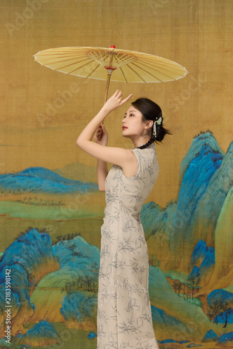 Fotografie Young woman in traditional Chinese qipao holding paper umbrella