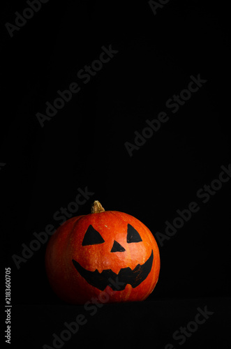Spooky Halloween jack-o'-lantern glowing on a dark black background with dramatic lighting and ample copy space. Traditional Halloween decoration creating an eerie, mysterious atmosphere.