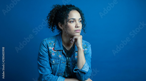 Pensive Young Woman with Curly Hair in Denim Jacket