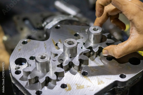 Foto Technician assembling three meshing spur gears onto hydraulic pump housing inside workshop