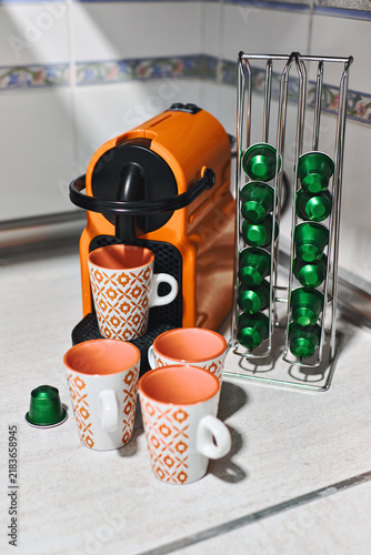Closeup of espresso machine, coffee mugs and aluminum capsules on kitchen counter