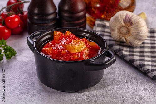 Cuadro en lienzo Black ceramic bowl filled with chunky red and yellow lecho beside fresh cherry t