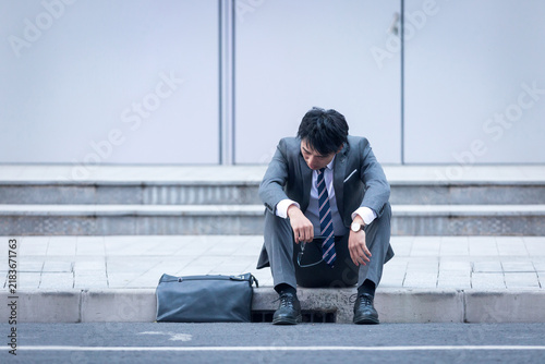 Businessman Sitting on City Steps Looking Down Sadly